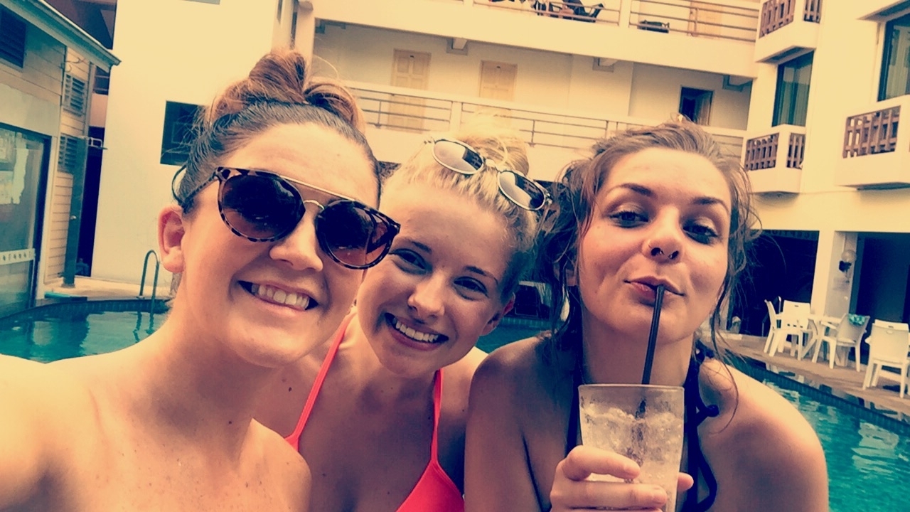 Three friends enjoying drinks by the poolside.