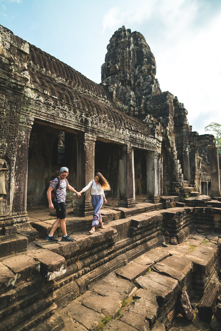 Couple exploring ancient temple ruins hand in hand.