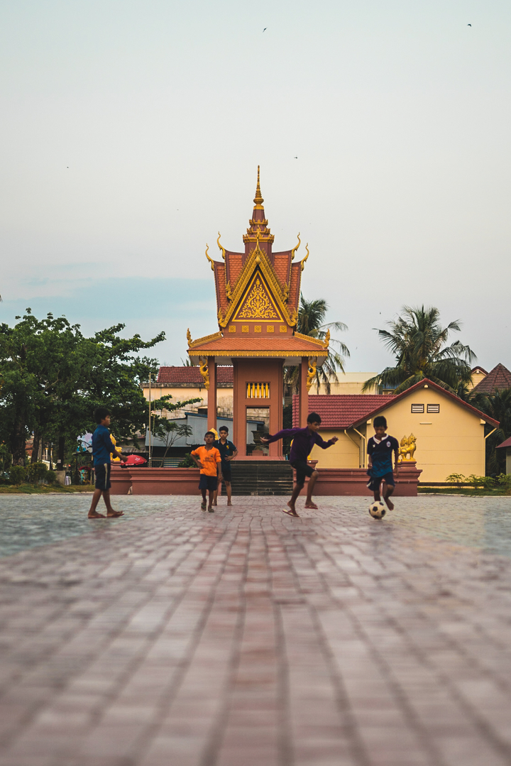 Children playing soccer in front of a temple.