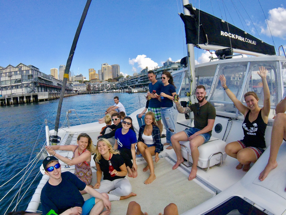 Group of people on a boat with Sydney skyline in background.
