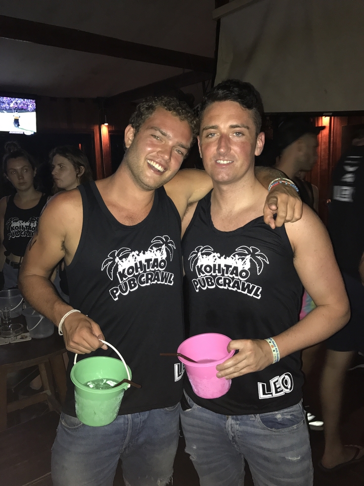 Two people posing for a photo wearing 'Koh Tao Pub Crawl' shirts.