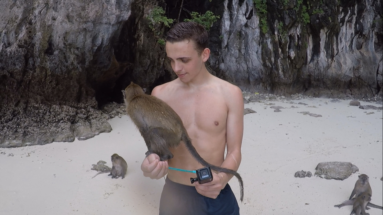 Man with a monkey in a beach setting.