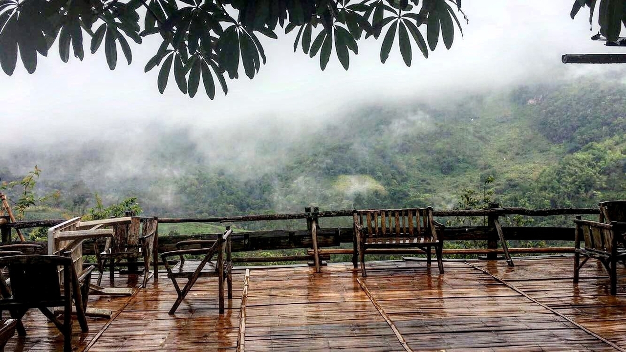Wet wooden terrace with misty green hills in the background.