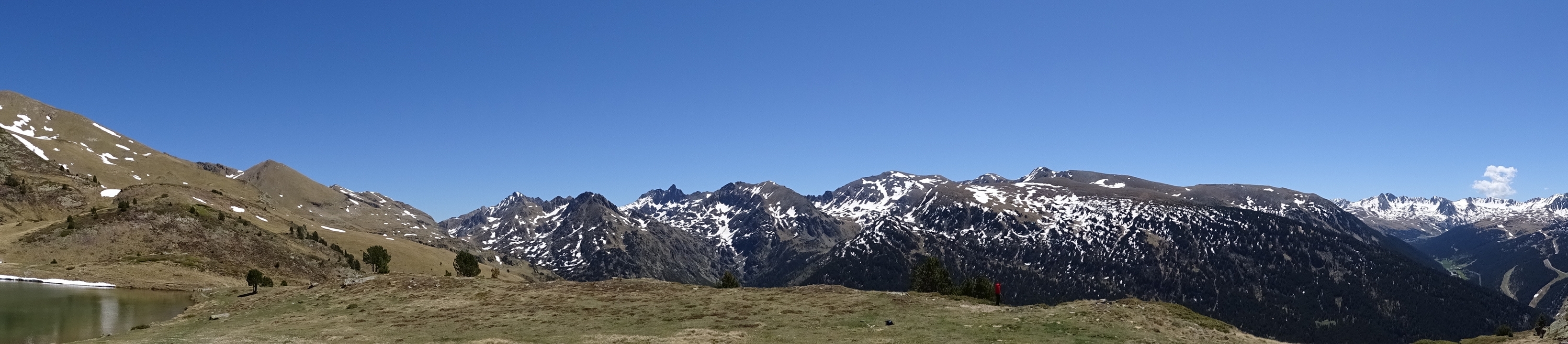 Paysage montagneux avec des plaques de neige sous un ciel bleu clair.