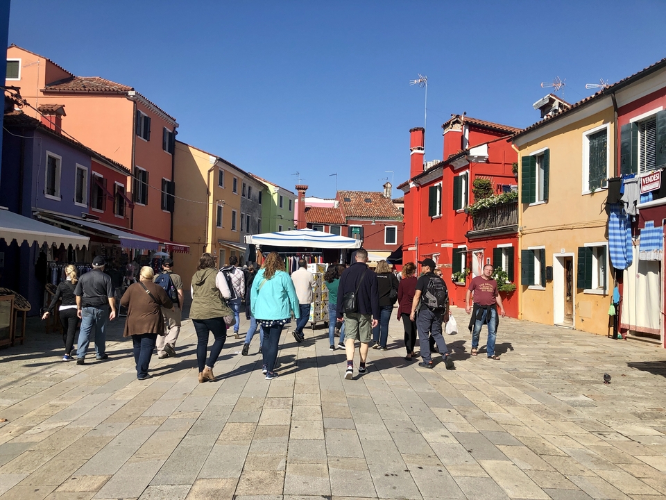 Tourists walking through a vibrant and colorful street with buildings.