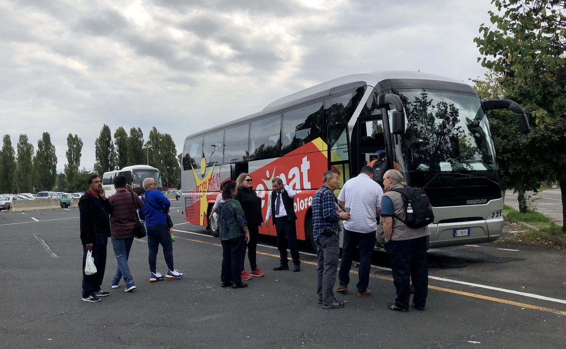 Group of people standing near a coach bus in a parking area.