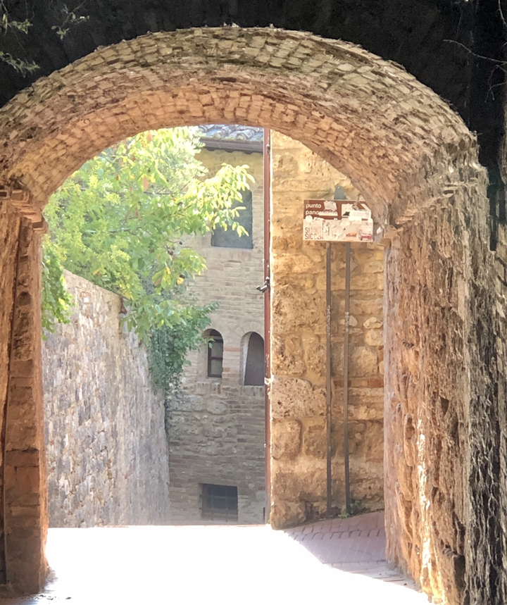 Stone pathway beneath an archway leading to buildings.