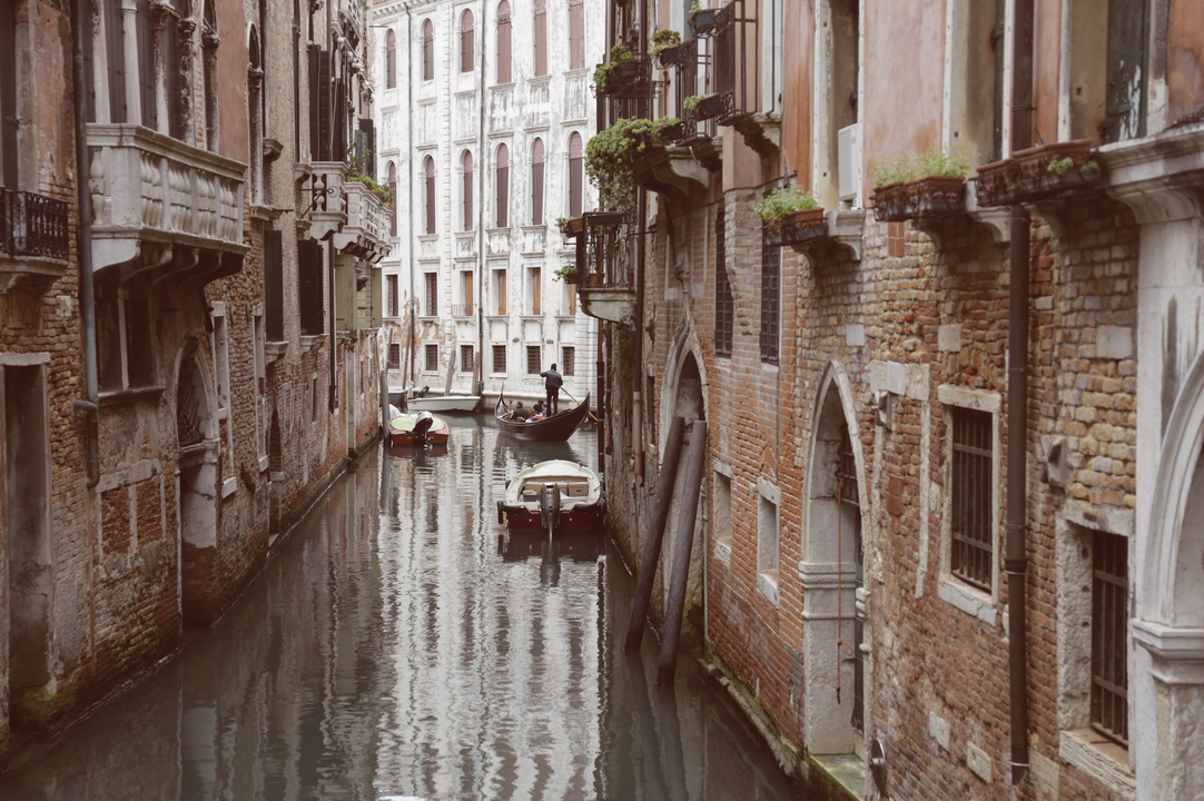 Gondolas in a canal with historic buildings on both sides.
