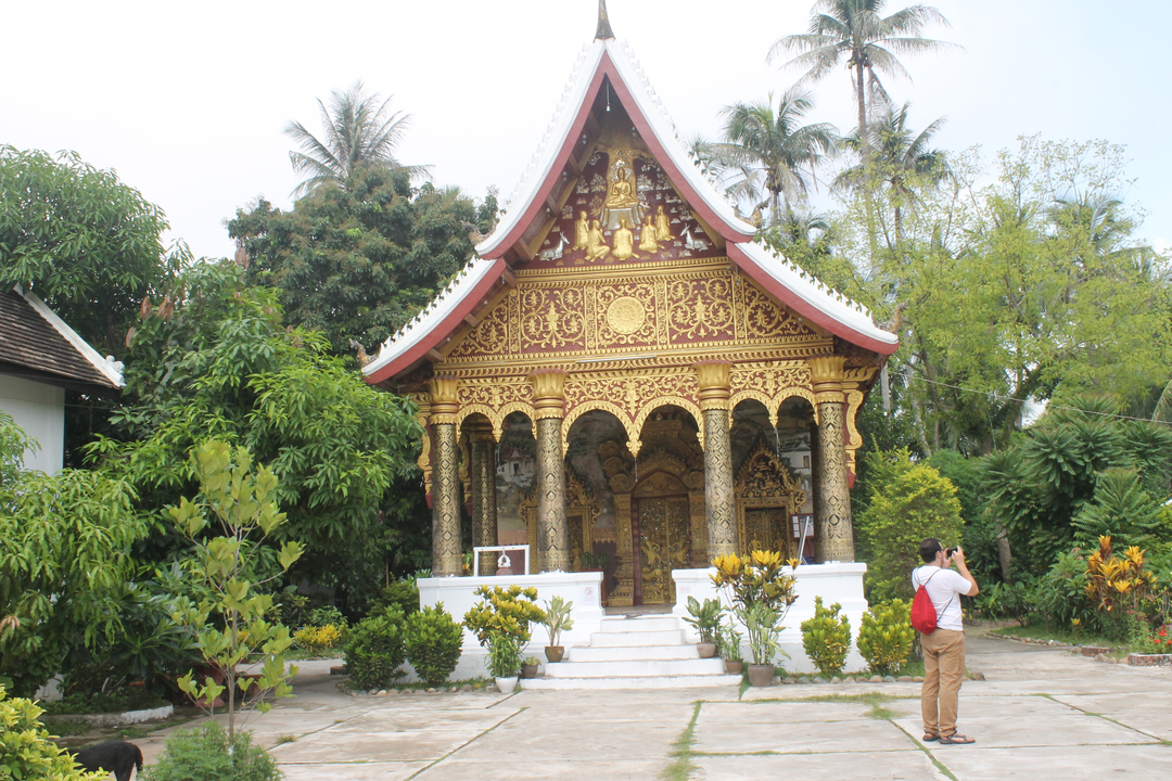 Tourist photographing a small, ornate temple.