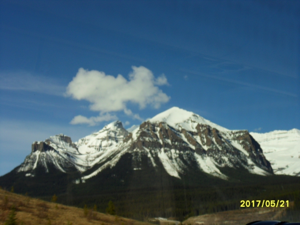 Image floue de montagnes enneigées sur fond de ciel bleu.
