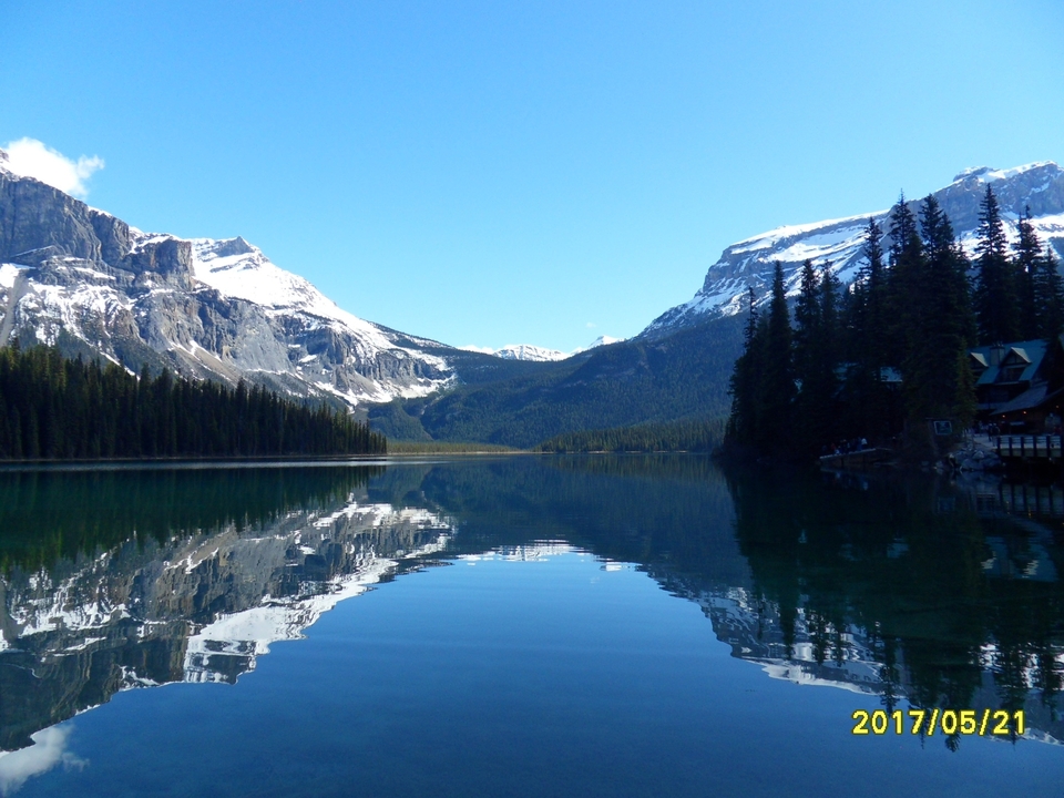 Vue panoramique d'un lac de montagne avec des reflets de pics enneigés.