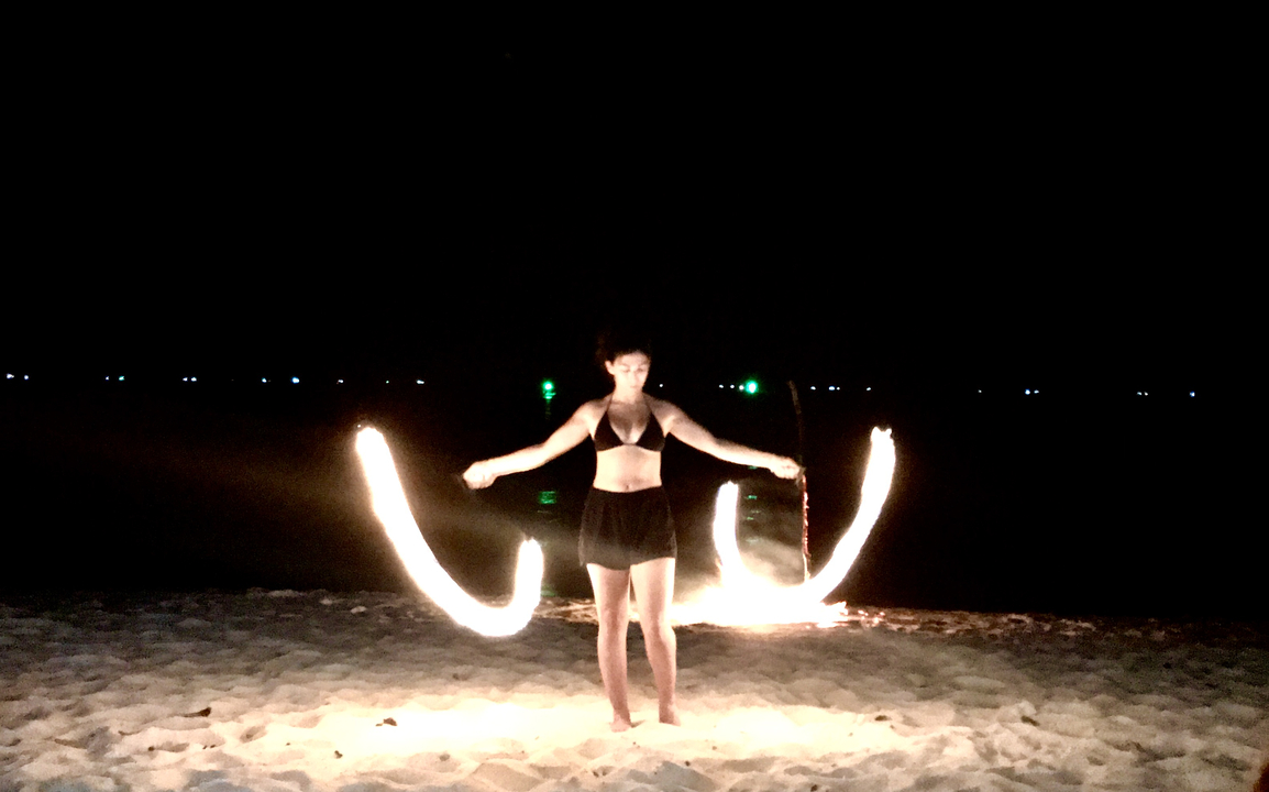 Person performing a fire dance on a beach at night.