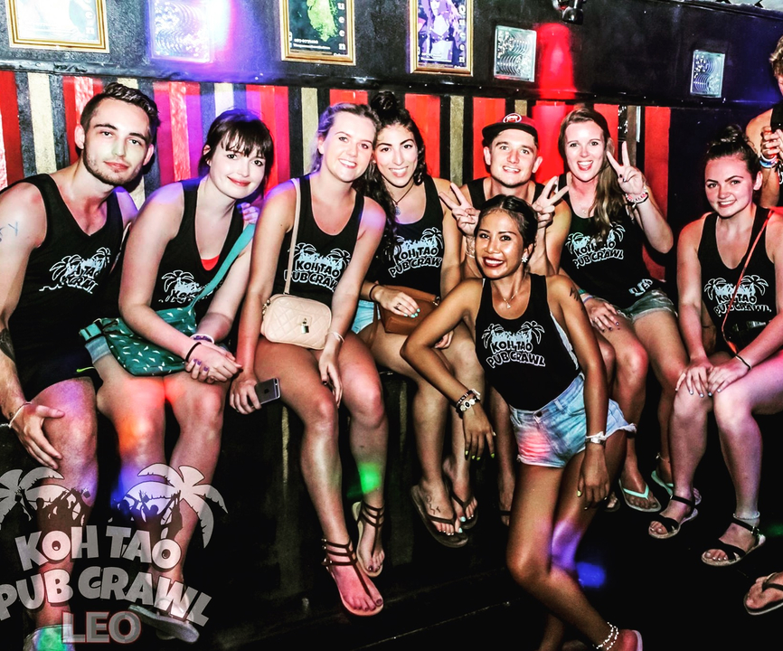 Group of friends with matching shirts posing at a pub crawl event.