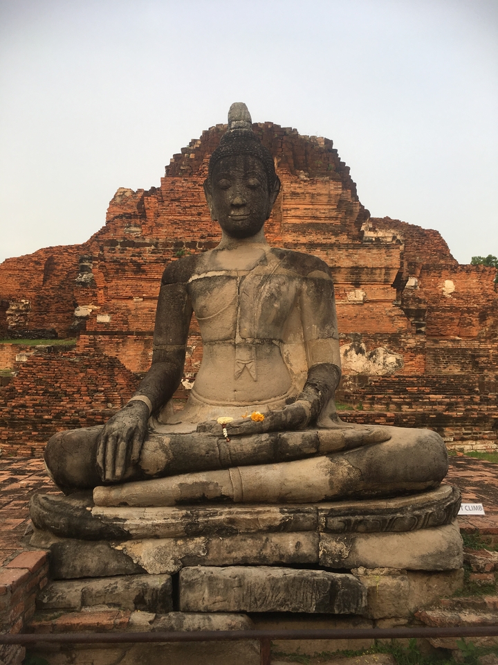 Buddha statue in front of ancient brick ruins.