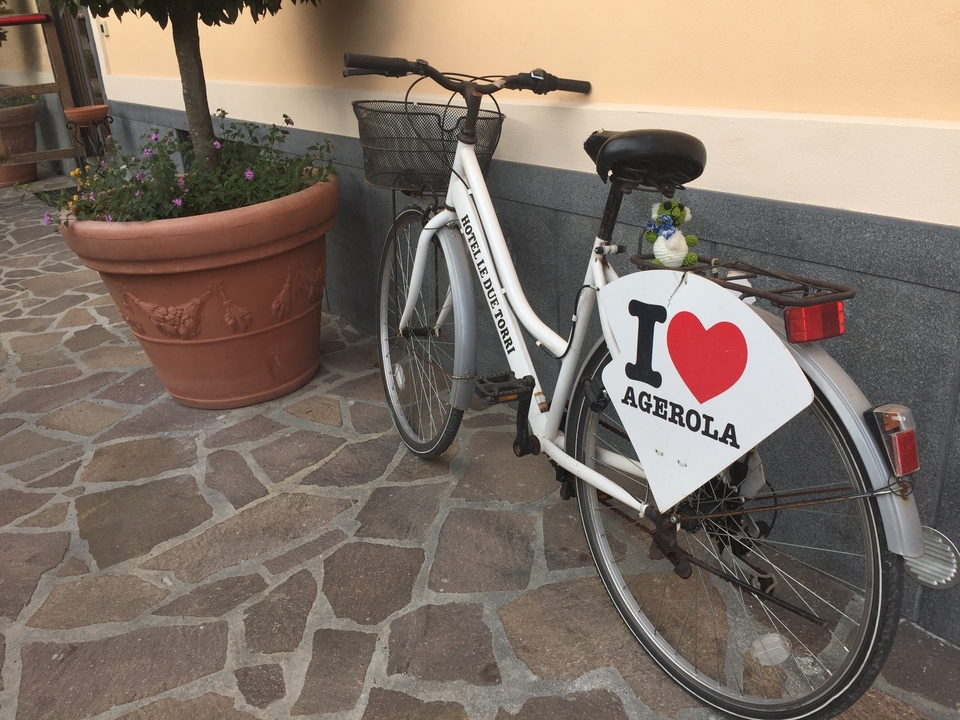 Bicyclette avec un panneau "I Love Agerola" garée contre un mur.