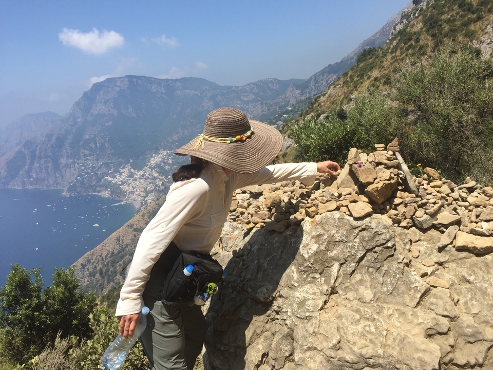 Femme sur un sentier de randonnée avec une vue pittoresque à flanc de falaise.