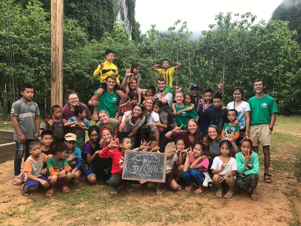 Large group of people including children smiling and posing outdoors.