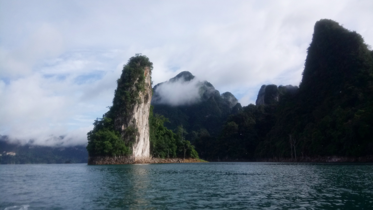 Tall limestone cliffs rising from the ocean under cloudy skies.