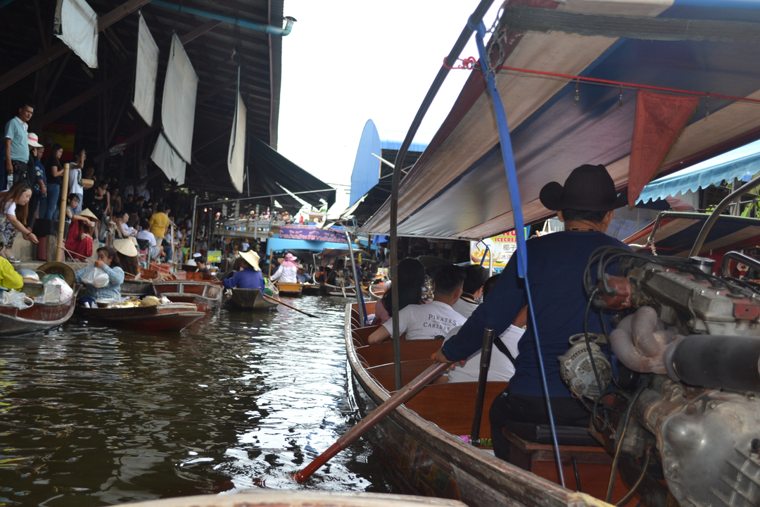 Scène animée sur un marché flottant avec des bateaux et des gens.