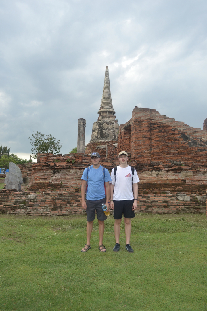 Two people standing in front of ancient brick ruins.