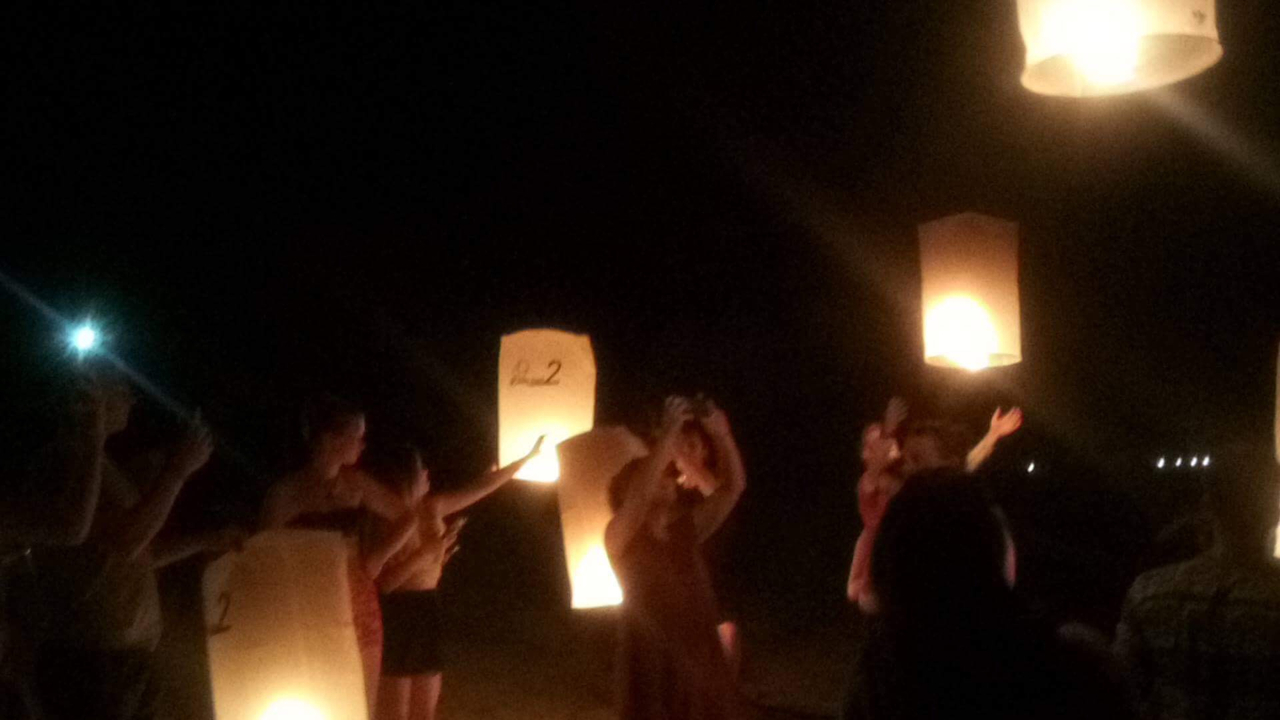 Des personnes lâchent des lanternes lors d'un événement nocturne.