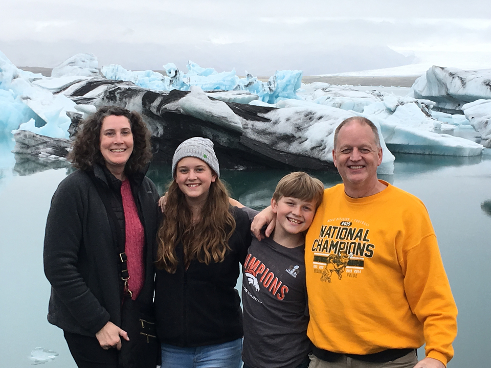 Family posing in front of icy lagoon.