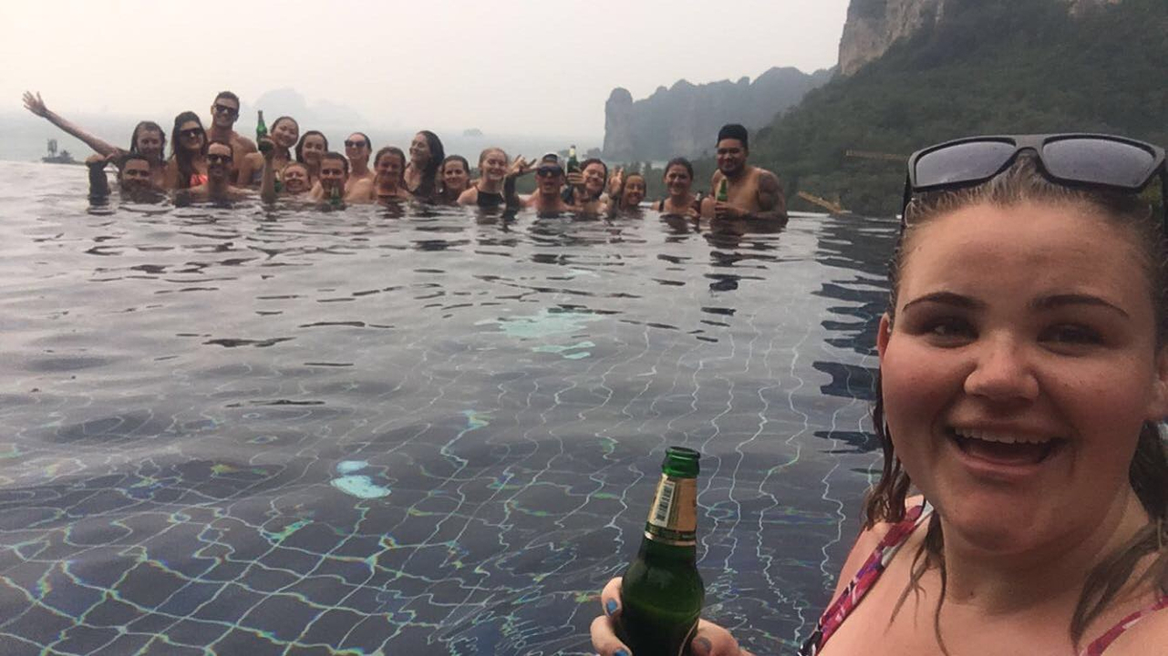 Group of people in an infinity pool with a scenic background.