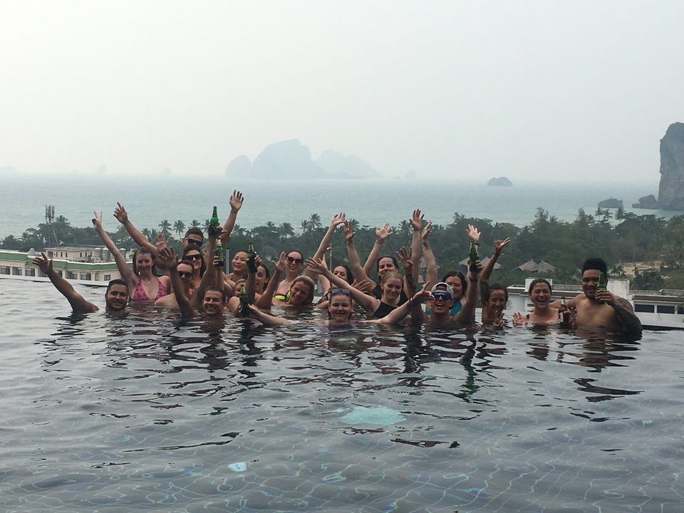 Large group of people in a pool with a mountainous background.