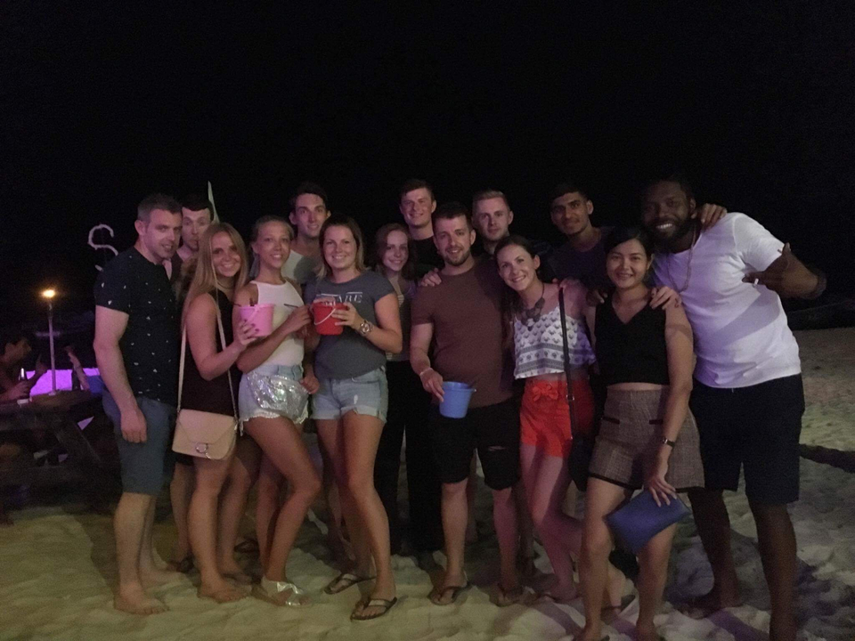 Group photo on a beach at night with dim lighting.