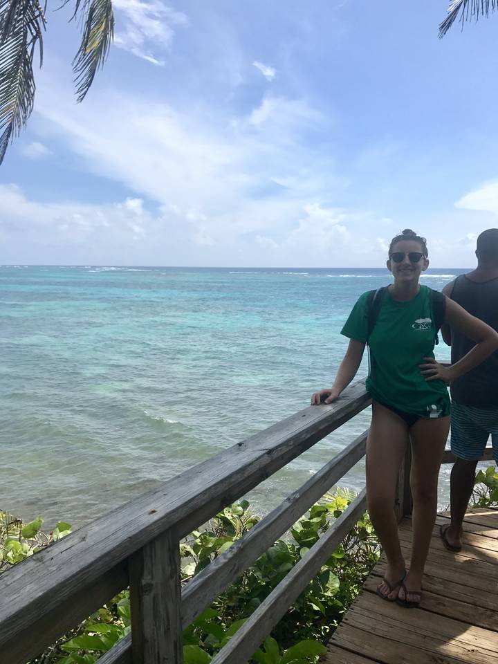 Woman standing on a wooden deck overlooking the ocean.