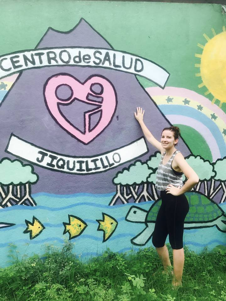 Woman posing beside a colorful mural with the word 'Jiquilillo'.