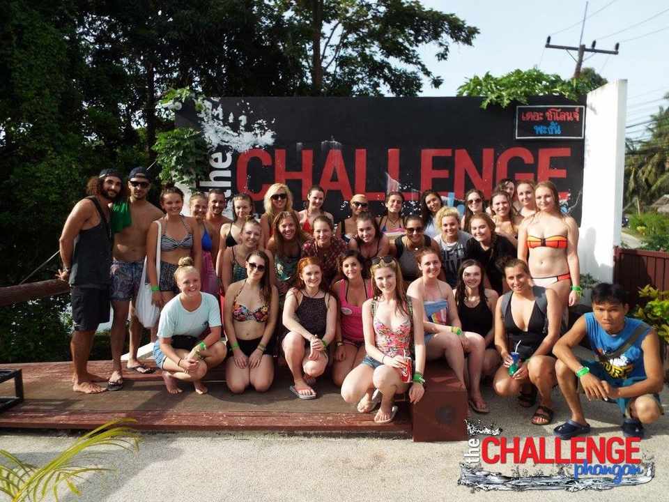 Group of people posing in swimwear in front of a sign.