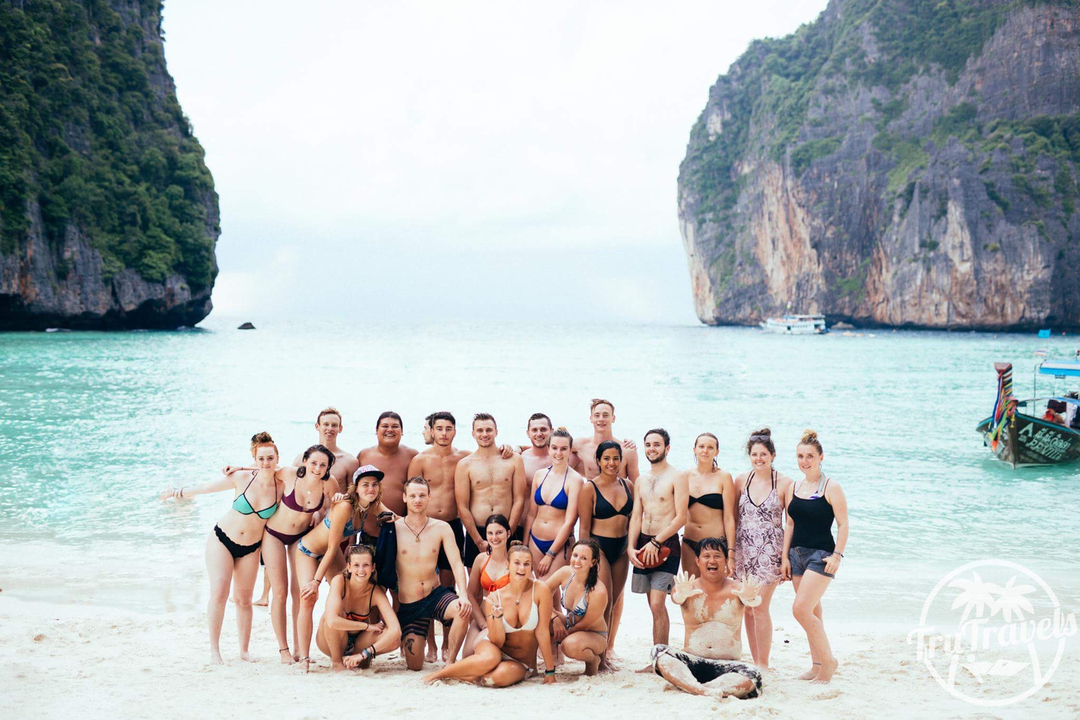 Large group of people posing on a beach.
