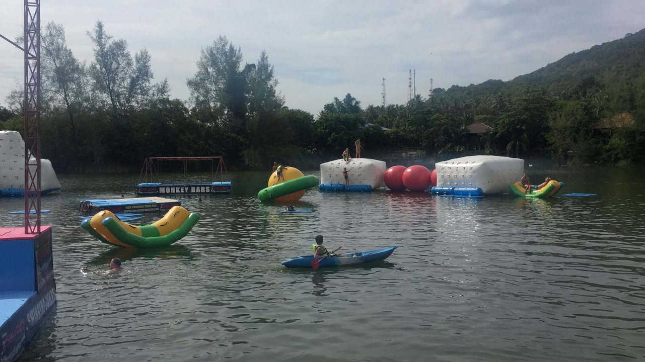 People kayaking and playing on inflatable water structures.