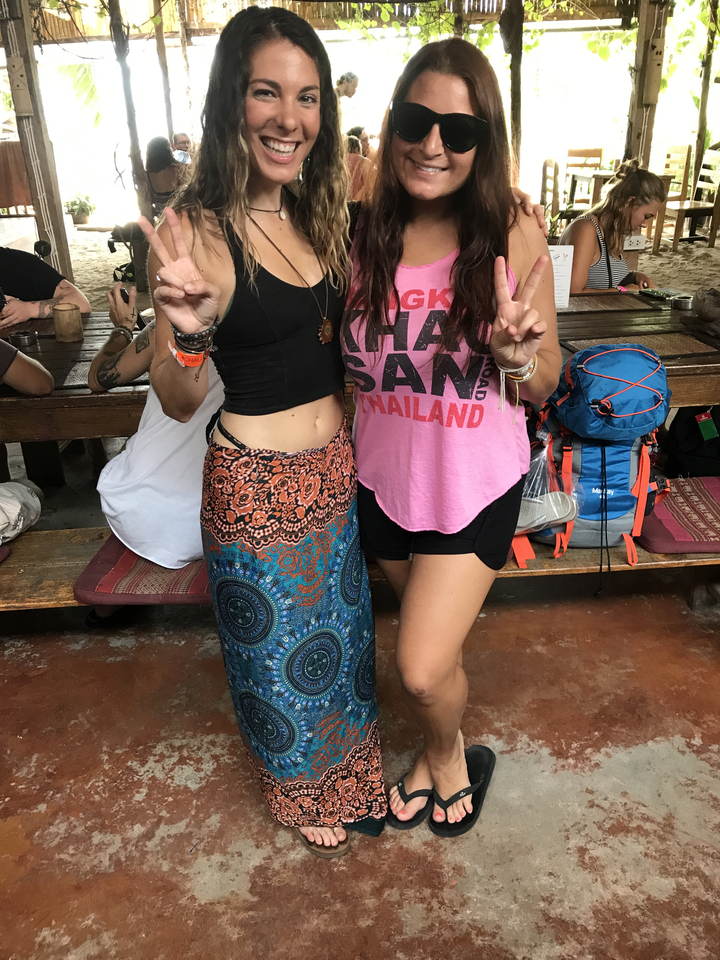 Two people showing peace signs wearing a shirt with Thailand written on it.