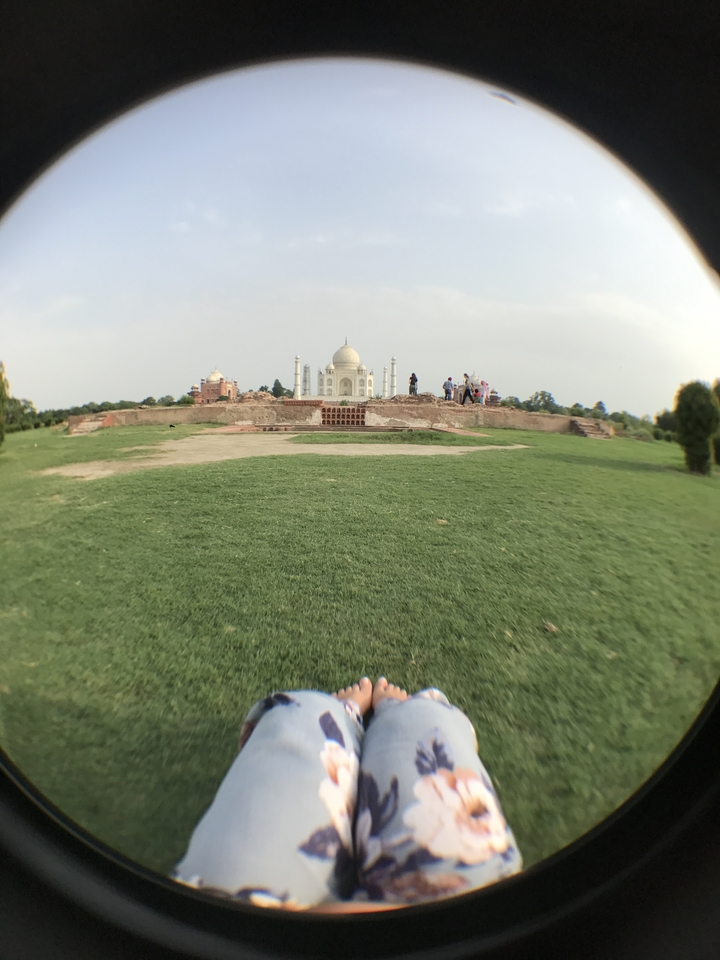 Vue lointaine du Taj Mahal avec des personnes au premier plan.