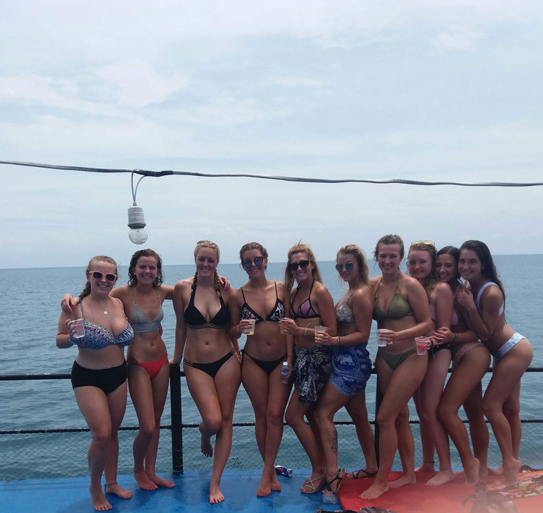 Group of friends posing on a boat with the sea as a backdrop.