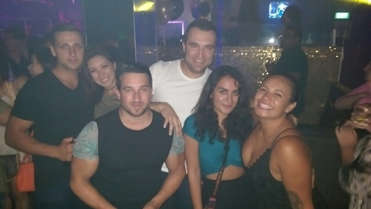 Group of people posing in a dimly lit room.