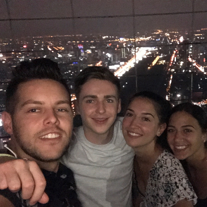 Group selfie with a cityscape at night.