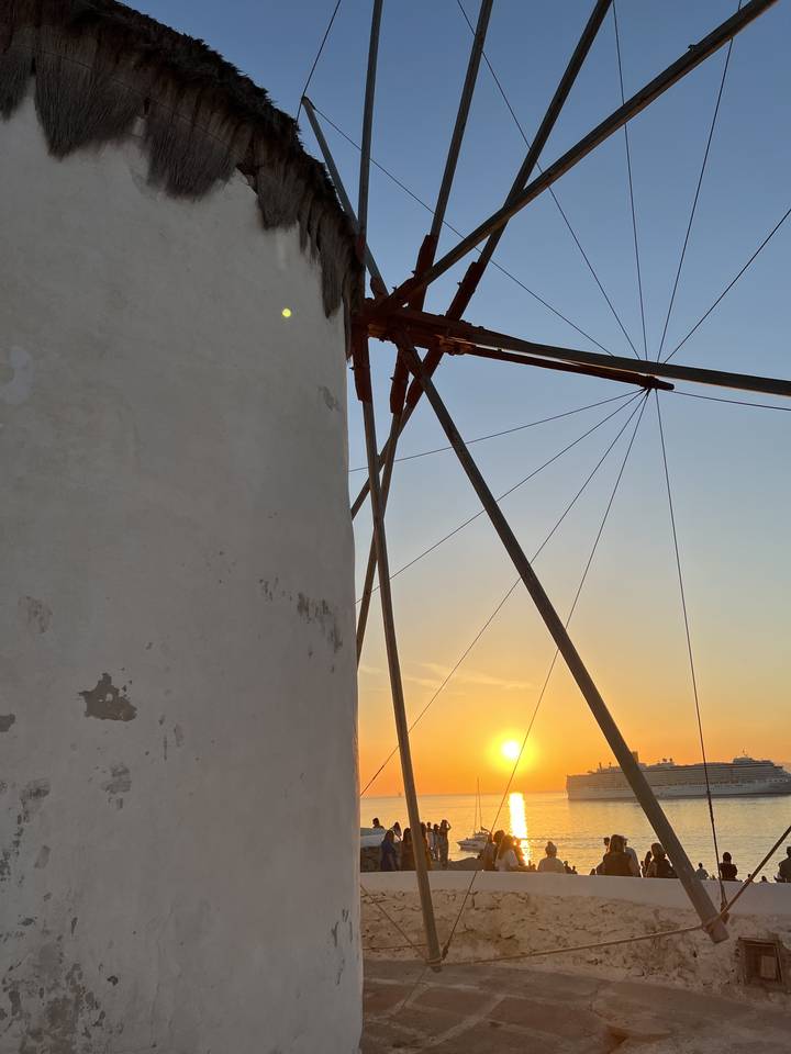 View of a windmill at sunset by the sea.