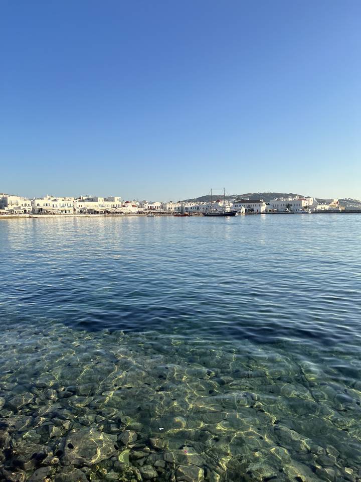 Clear blue waters by the coast with buildings in the background.