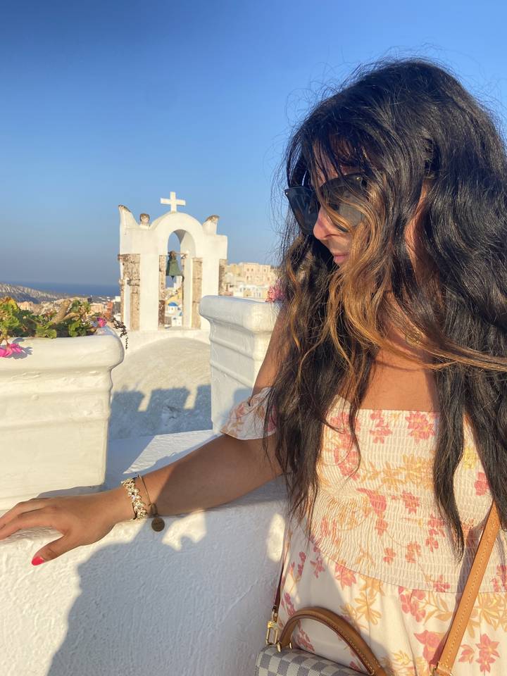 Close-up of a woman with sunglasses and a church in the background.