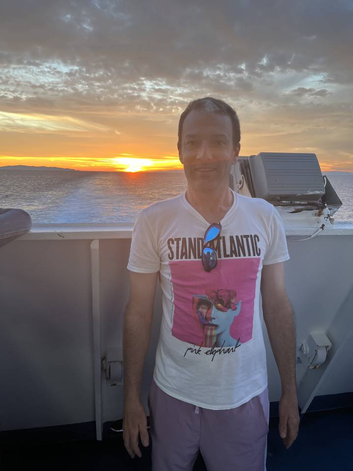 Man posing in front of a sunset on a boat.