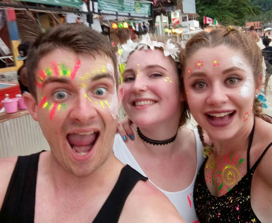 Three people with face paint posing for a joyful photo.