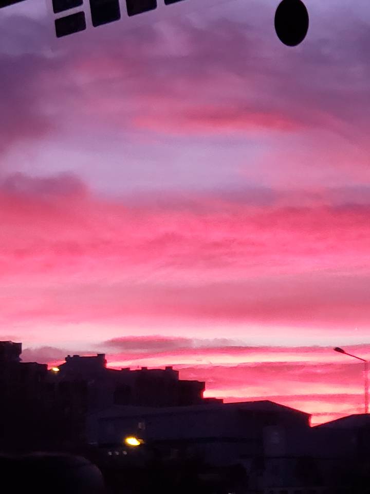 A vertical image of a red and pink sunset with part of a building.