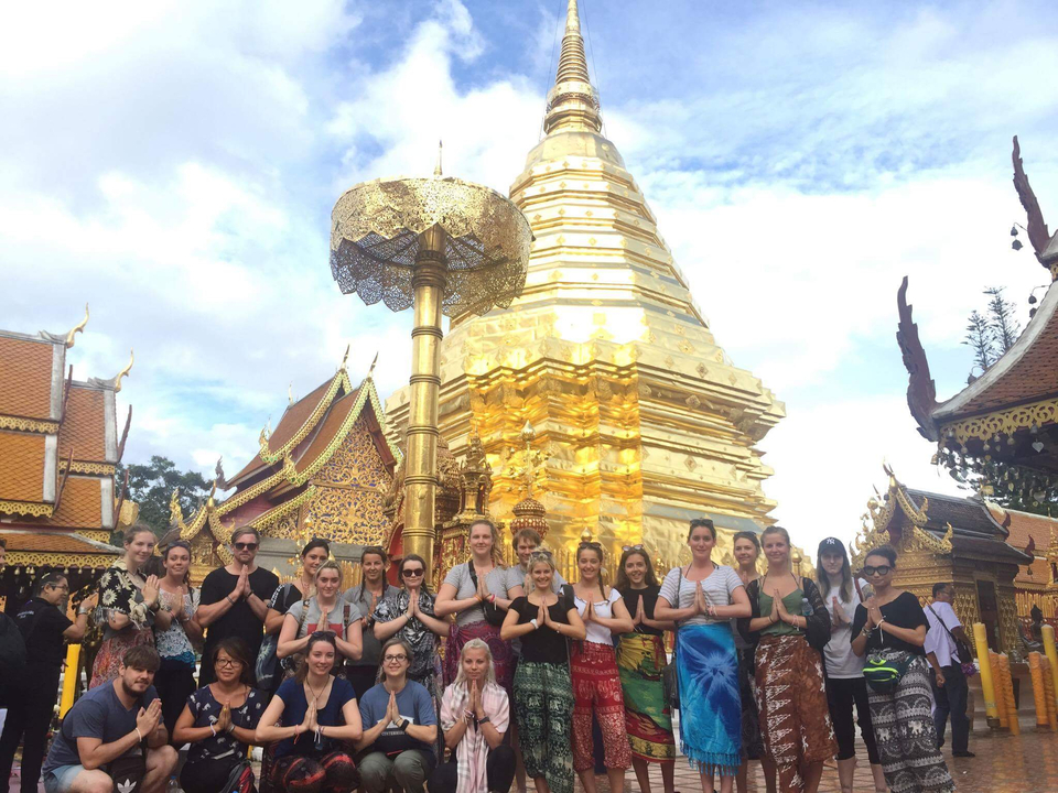 Group of people posing in front of a golden temple.