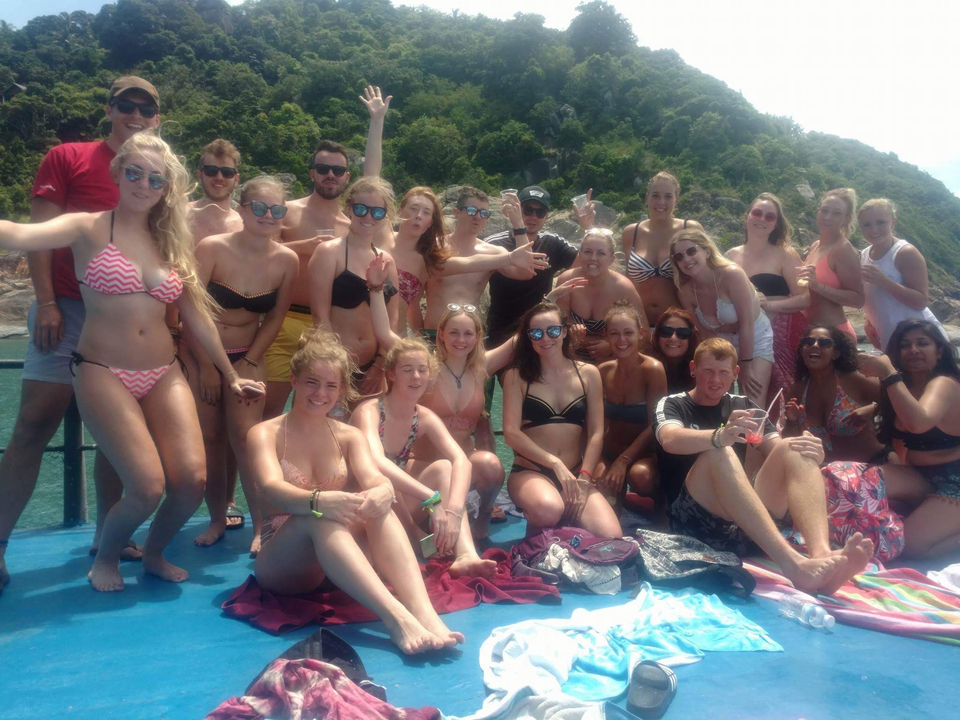 Large group of people on a boat with mountains in the background.