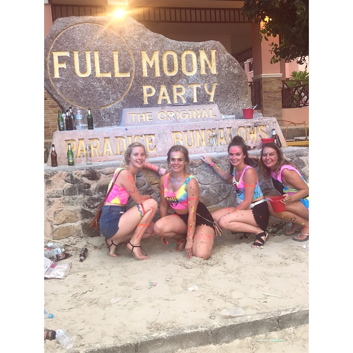Group of people posing in a party setting in front of a sign.
