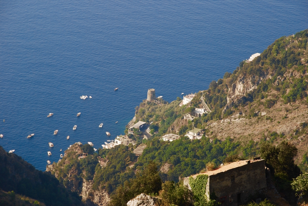 Vue en plongée d'un village côtier avec des bateaux et un paysage luxuriant.