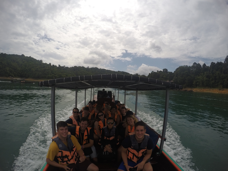 People on a boat with life jackets on a lake or river.